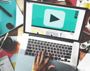 Hand typing laptop with play button screenTVC OnlineRich Media